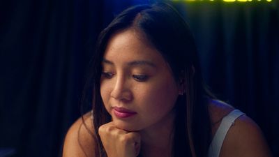 a woman sitting in front of a neon sign