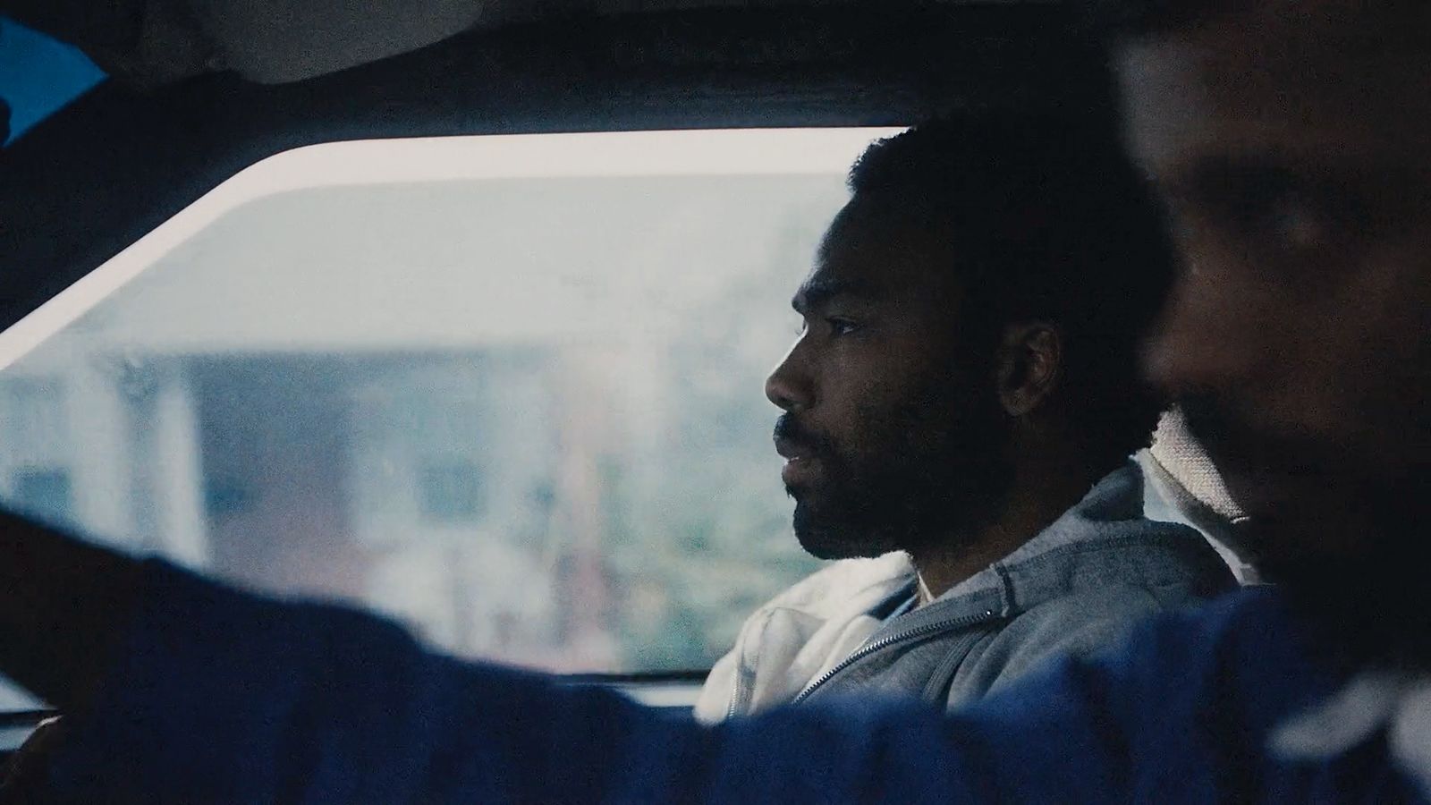 two men sitting in a car looking out the window