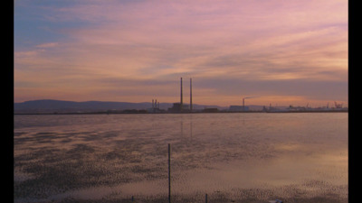 a large body of water with a factory in the background