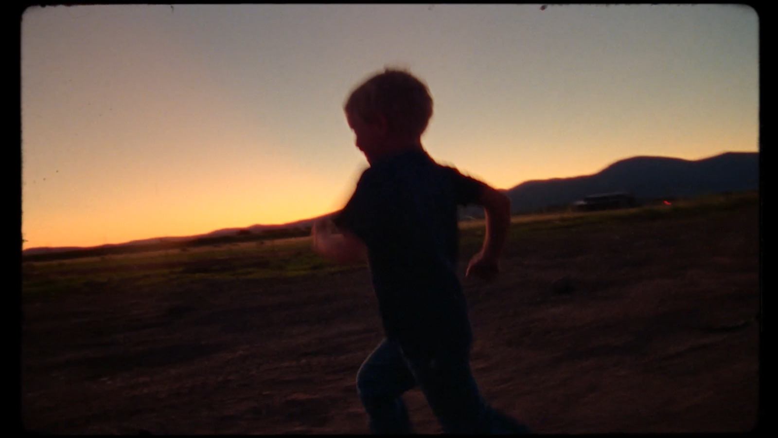 a young boy is playing with a frisbee at sunset