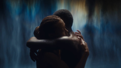 a man and a woman embracing in front of a waterfall