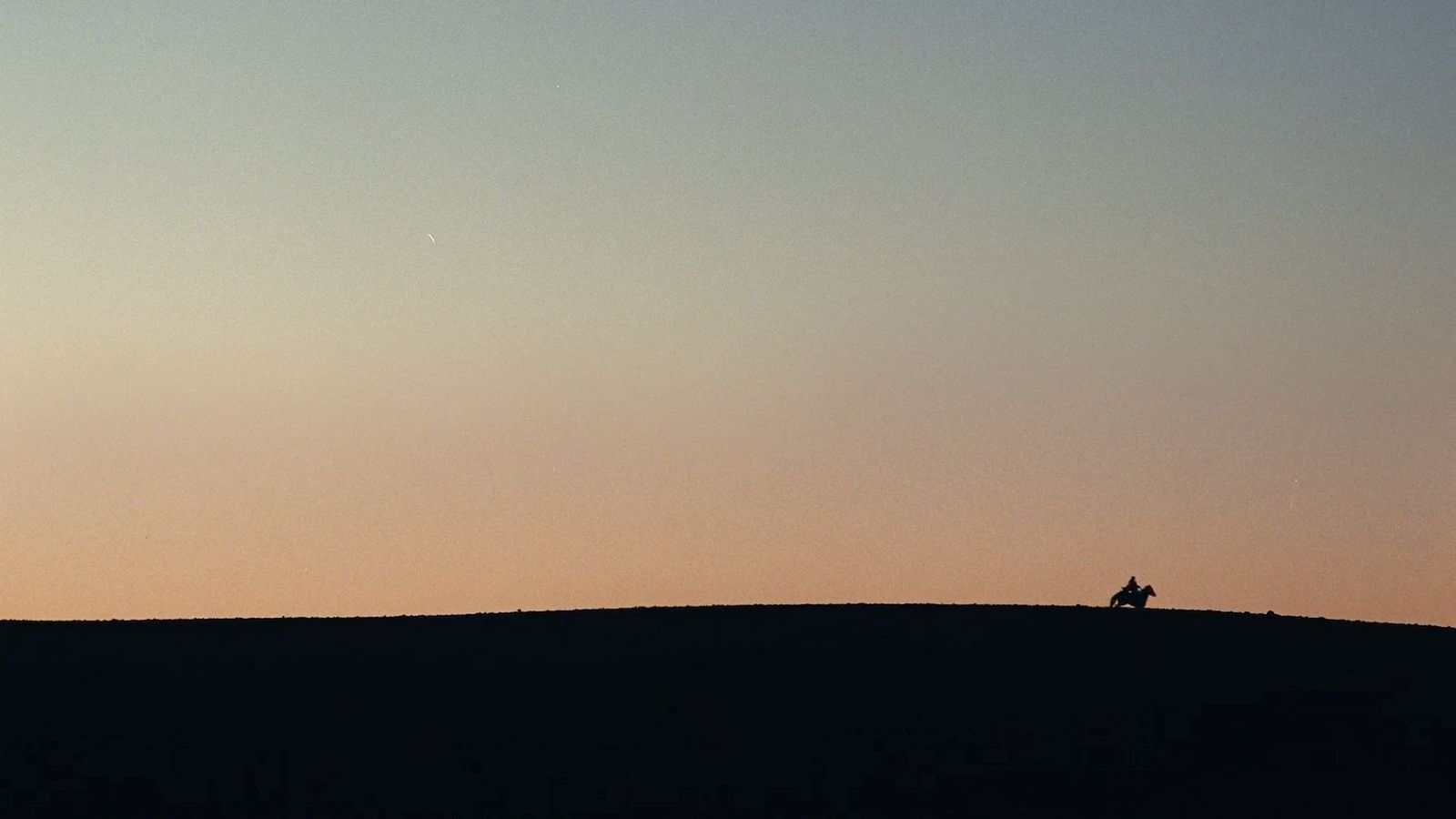 a person sitting on top of a hill at sunset