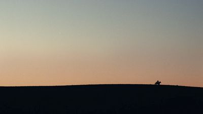 a person sitting on top of a hill at sunset