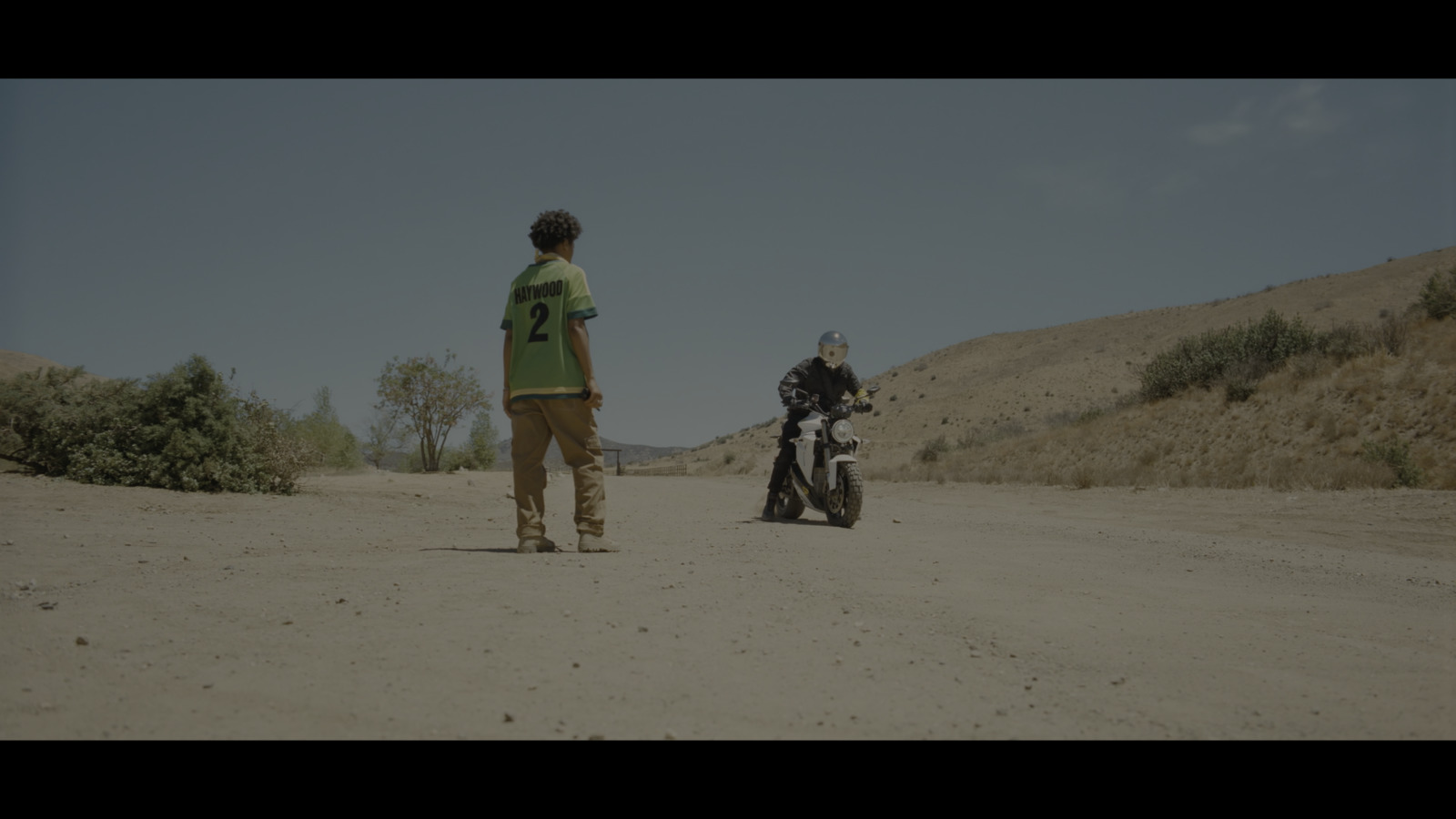 a man standing next to a motorcycle on a dirt road