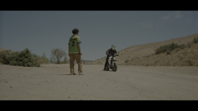 a man standing next to a motorcycle on a dirt road