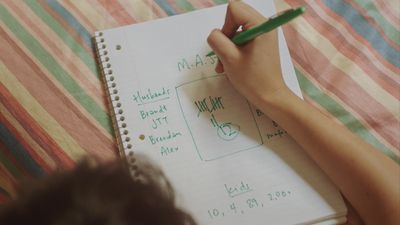 a person writing on a notebook with a green pen