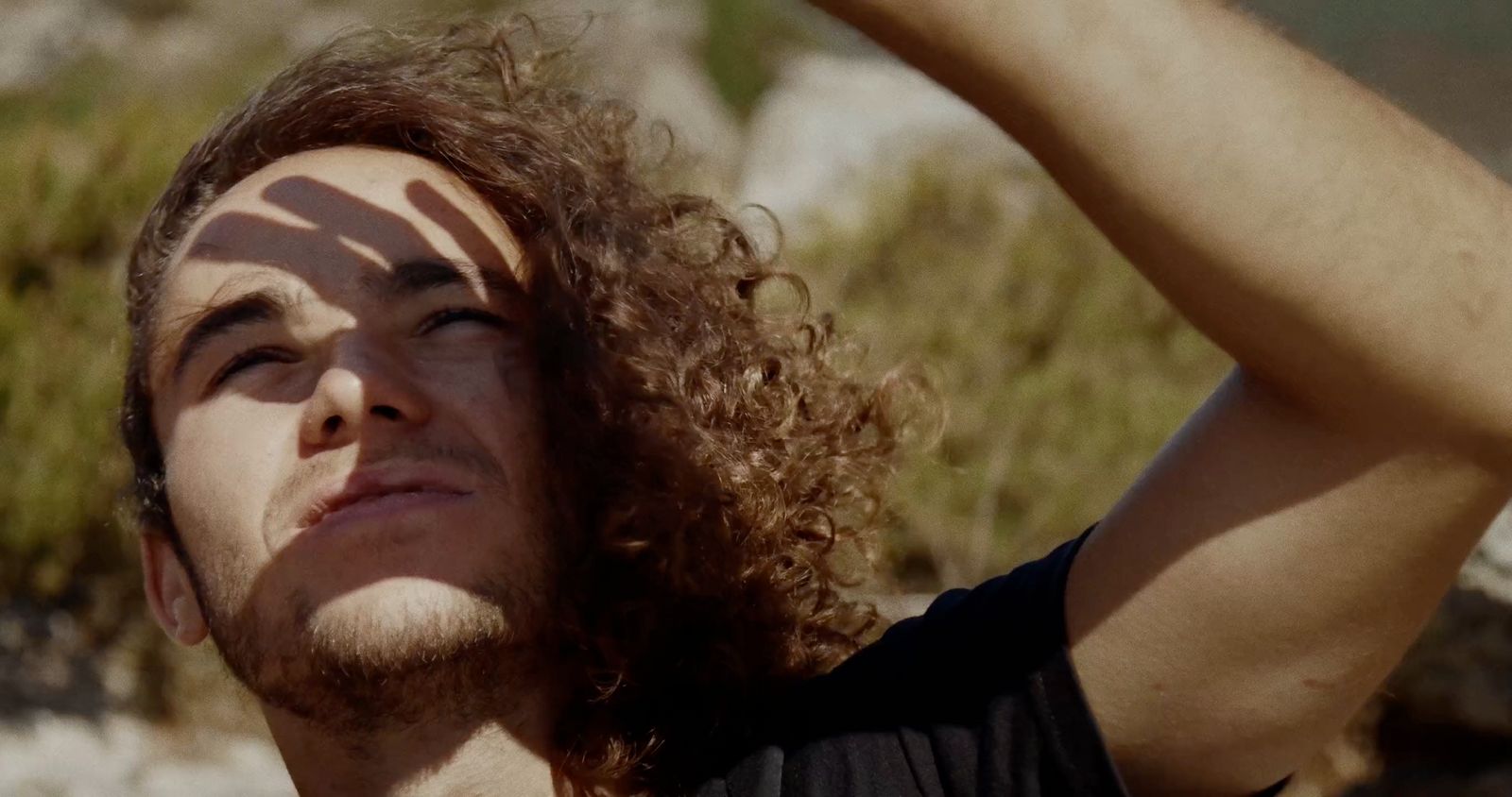 a man with curly hair and a black shirt