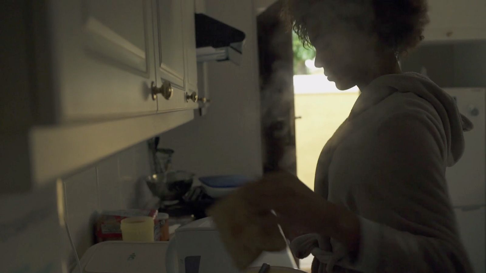 a woman standing in a kitchen preparing food