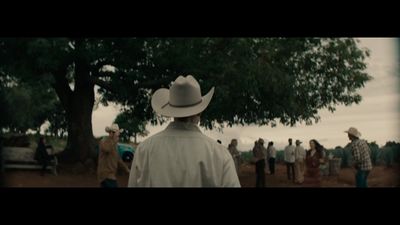 a man wearing a cowboy hat standing in front of a group of people