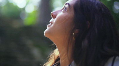 a woman looking up in the air with trees in the background