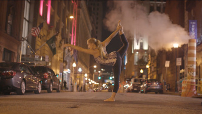 a woman doing a dance pose on a city street