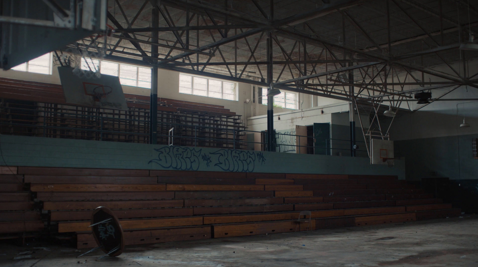 a basketball court with wooden benches and graffiti on the wall