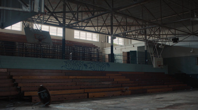 a basketball court with wooden benches and graffiti on the wall