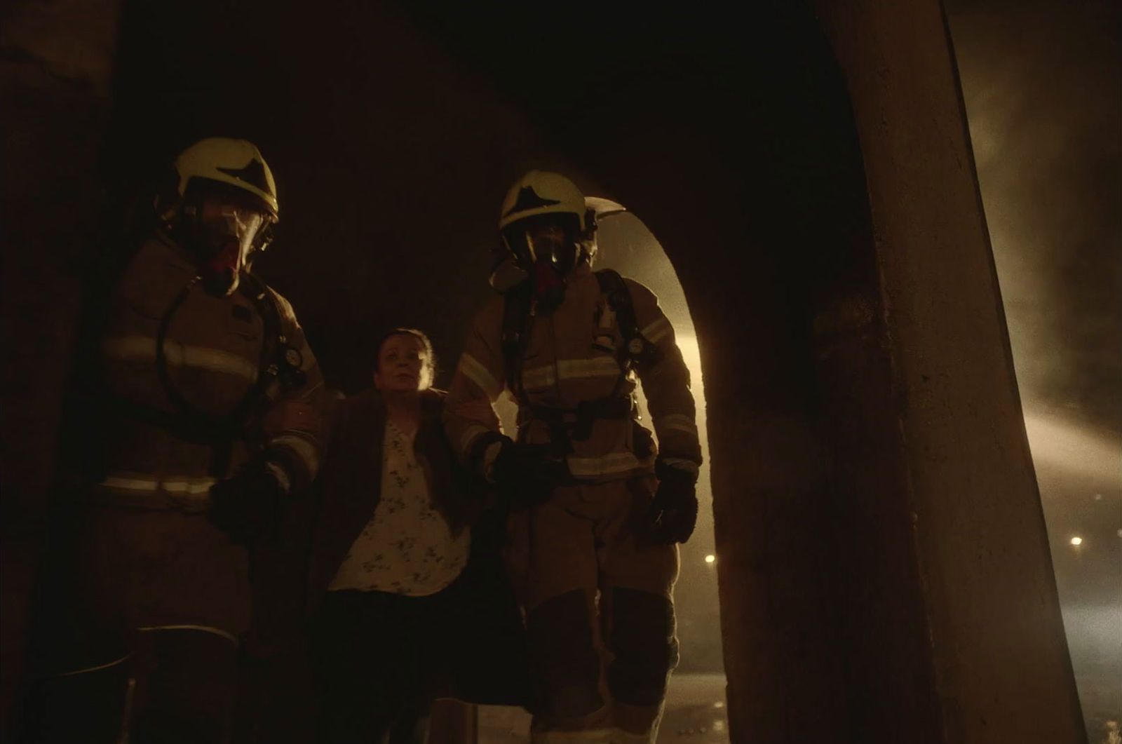 a woman standing next to two firemen in a tunnel