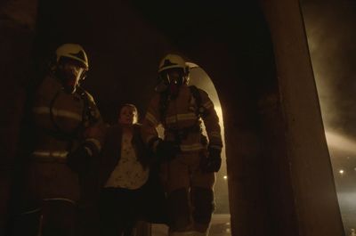 a woman standing next to two firemen in a tunnel