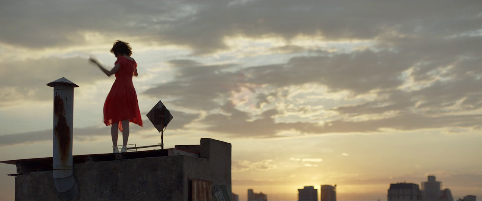 a woman in a red dress standing on top of a building