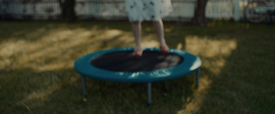 a little girl jumping on a trampoline in a yard