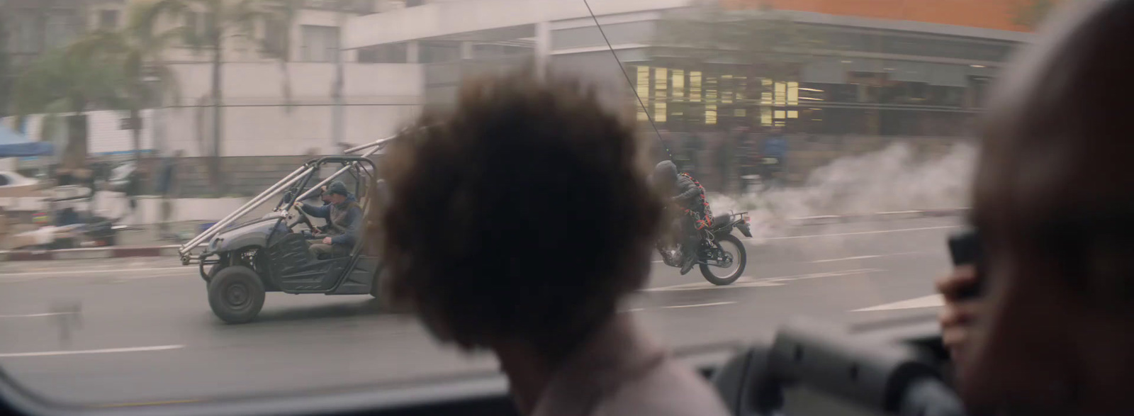 a man driving a motorcycle on a street with smoke coming out of it