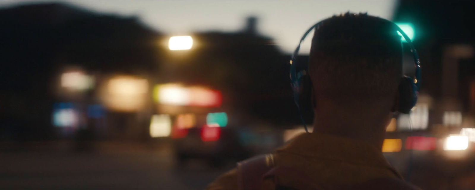 a man wearing headphones standing on a street at night