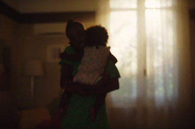 a woman holding a child in her arms in front of a window