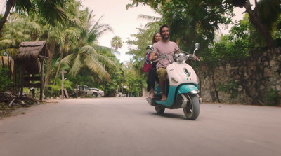 a man and a woman riding a scooter down a street