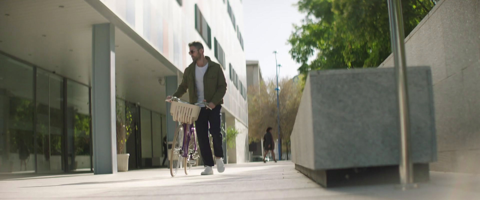 a man riding a bike down a street next to a tall building