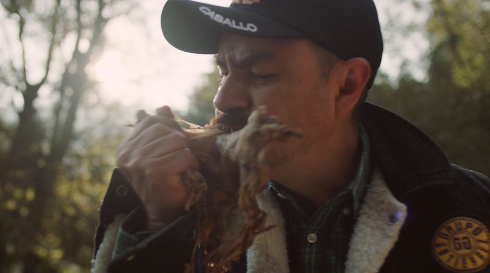 a man eating a piece of food in the woods