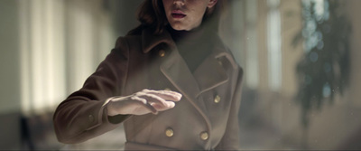 a woman in a trench coat looking in a mirror