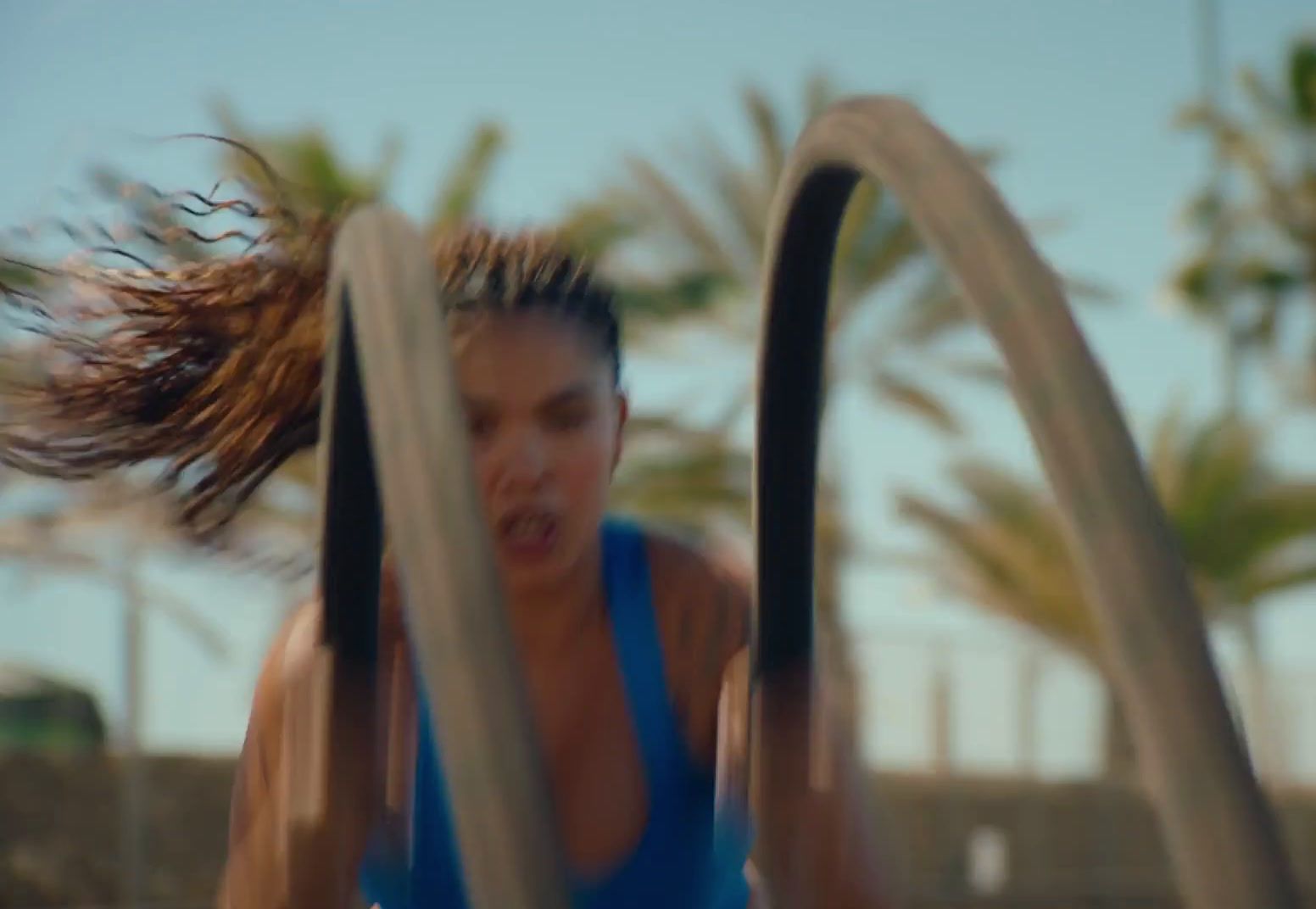 a woman in a blue tank top is doing a trick on a trampoline