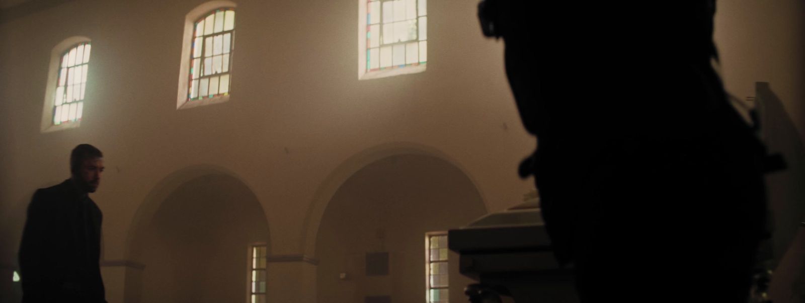 a man standing in a room with three windows