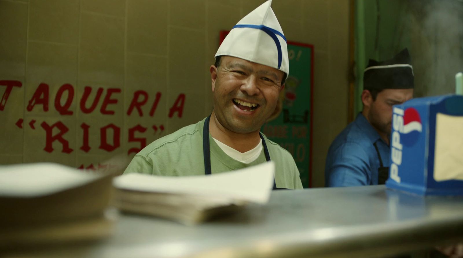 a smiling man wearing a chef's hat in a restaurant