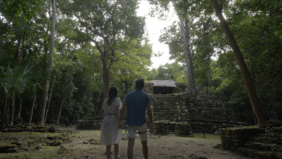 a man and a woman walking through a forest