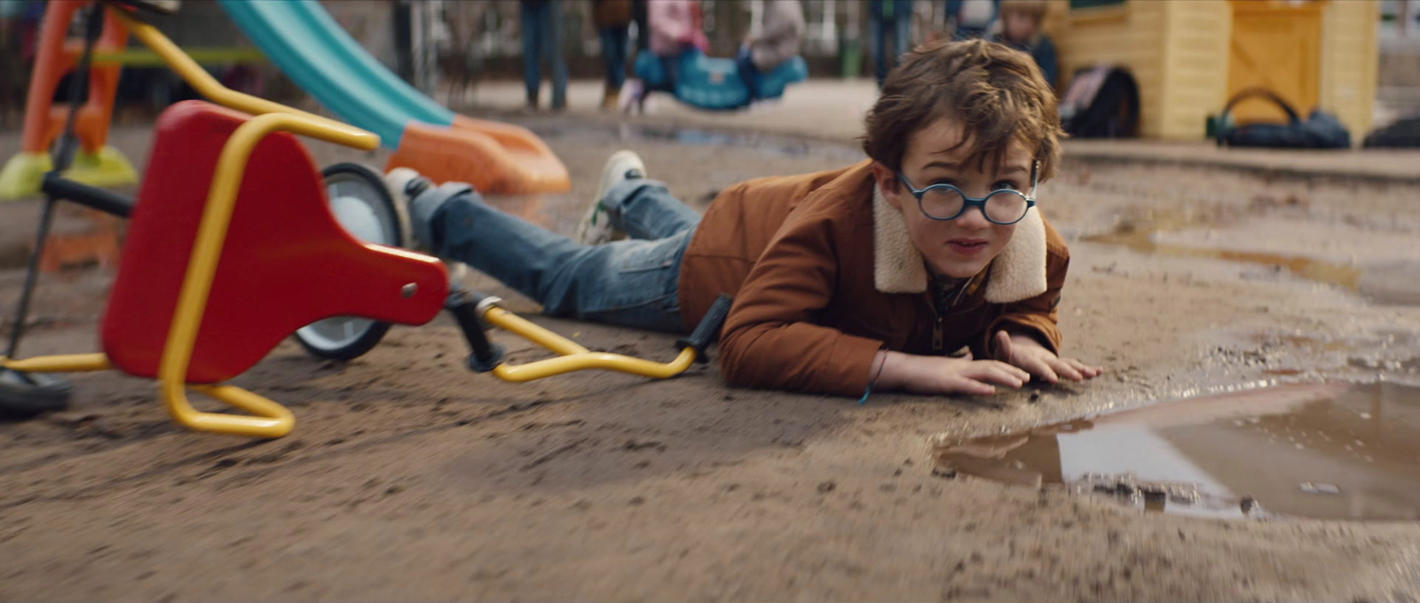 a young boy laying on the ground in a puddle