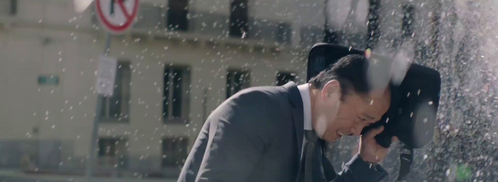 a man in a suit is standing under a water fountain