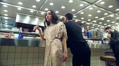 a woman in a gold dress standing in front of a counter