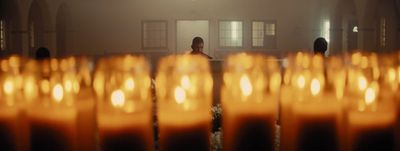 a man standing in front of a row of lit candles