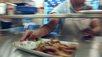 a person in a kitchen preparing food on a plate