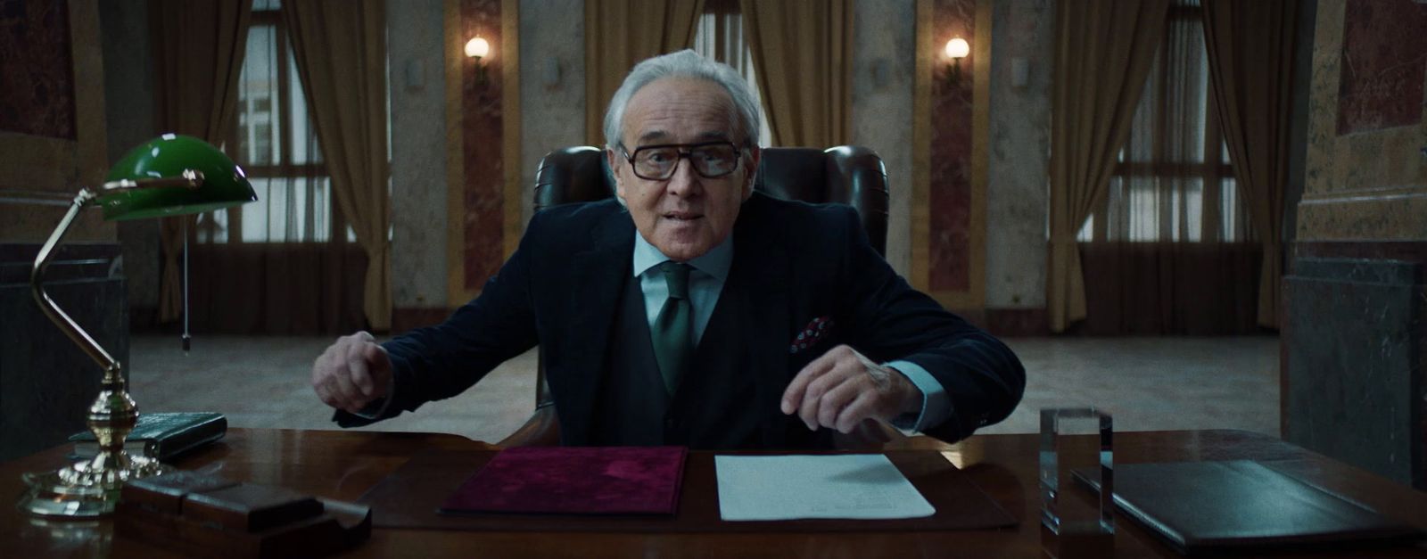 a man in a suit and tie sitting at a desk