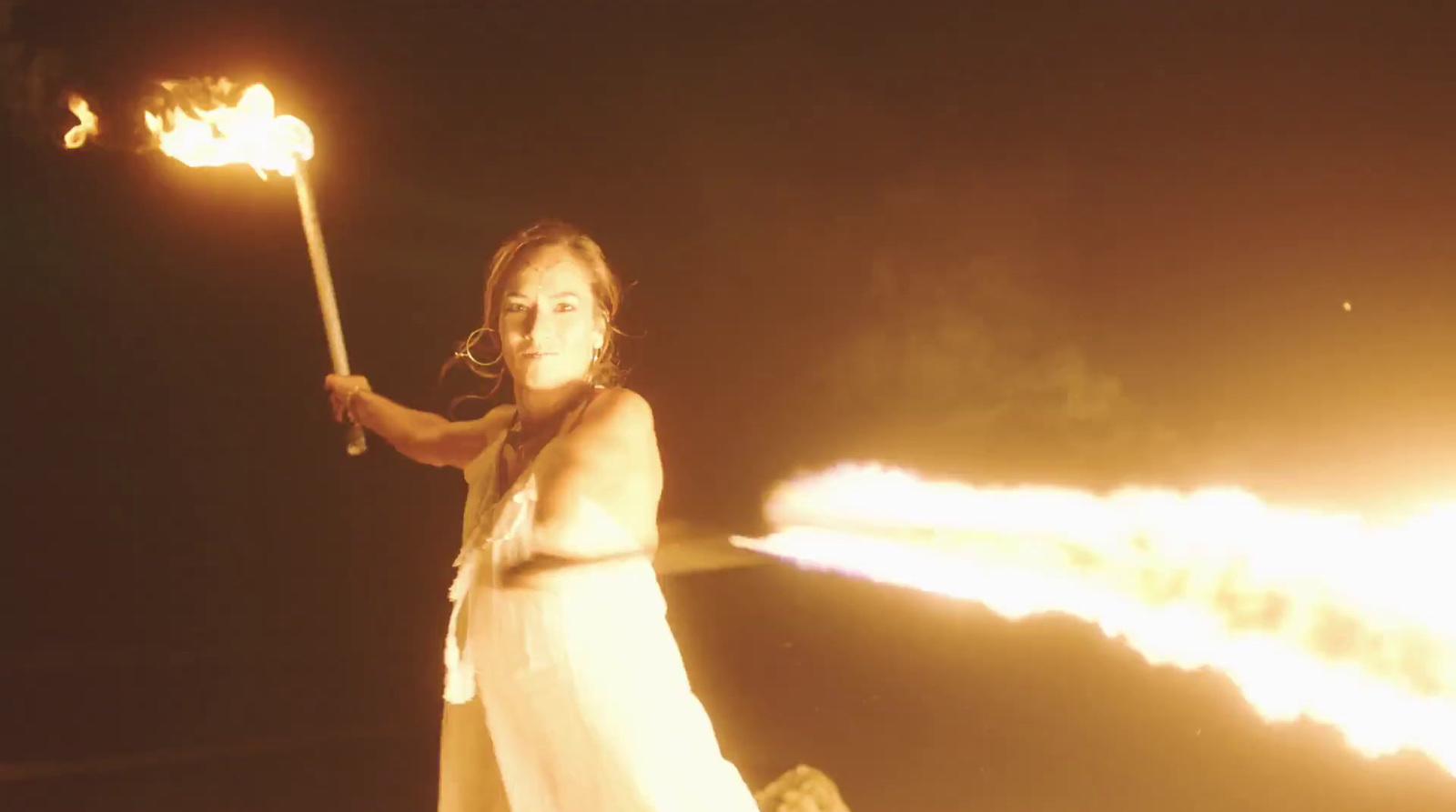 a woman in a white dress holding a fire stick