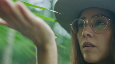 a woman wearing glasses and a hat holding a plant