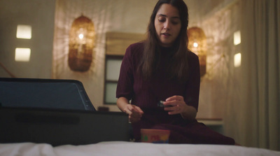 a woman sitting on a bed looking at a laptop