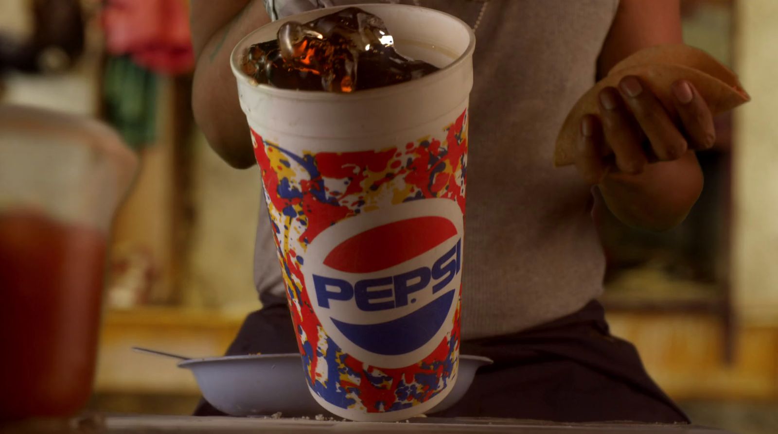 a person sitting at a table with a pepsi cup