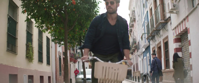 a man riding a bike down a street next to tall buildings