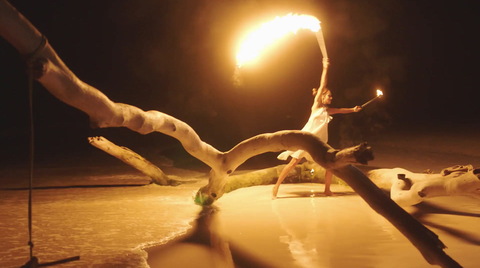 a woman doing a handstand on a beach at night