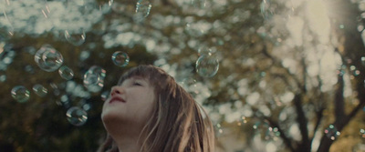 a young girl is blowing bubbles in the air