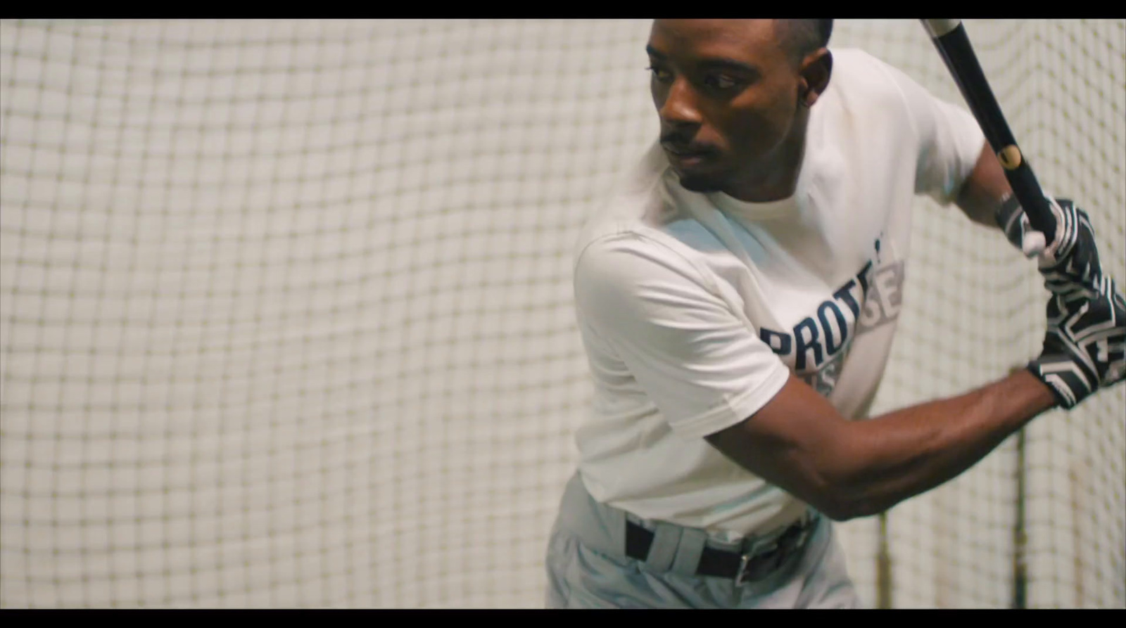 a man holding a baseball bat in a batting cage