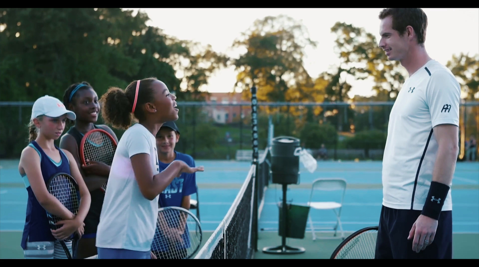 a group of people standing on a tennis court holding racquets