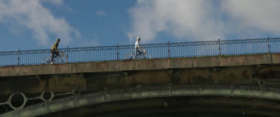 a couple of people riding bikes across a bridge