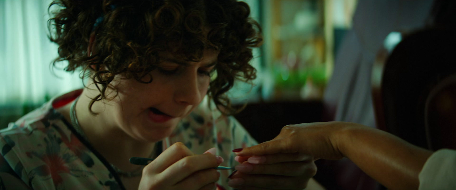 a woman with curly hair is getting her nails done