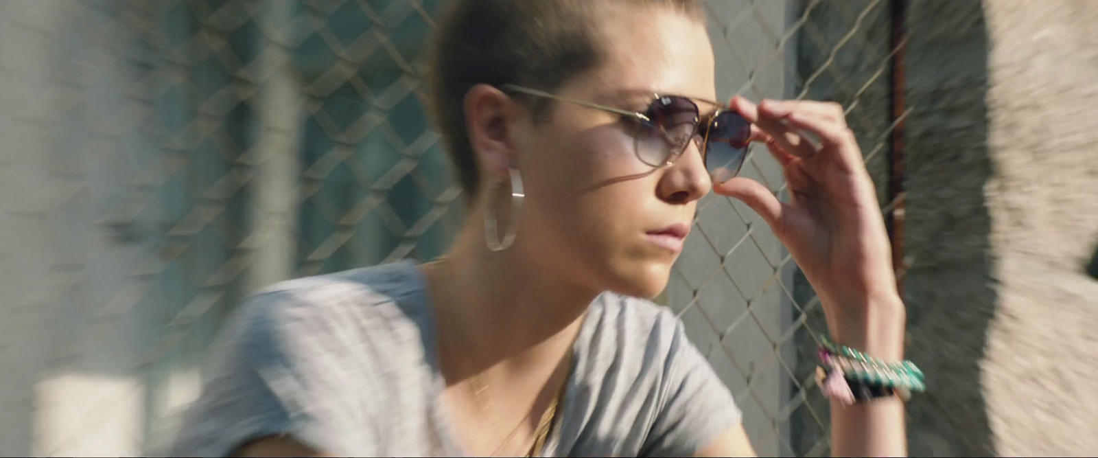 a woman wearing sunglasses leaning against a fence